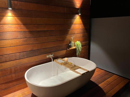 un bagno con vasca bianca e pareti in legno di Lagoon Haven - Waikanae Holiday Home a Paraparaumu Beach