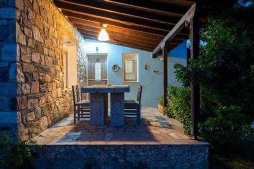 a stone patio with a table and chairs on a house at Malama Rooms in Sikia