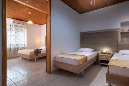 a bedroom with two beds and a mirror at Malama Rooms in Sikia