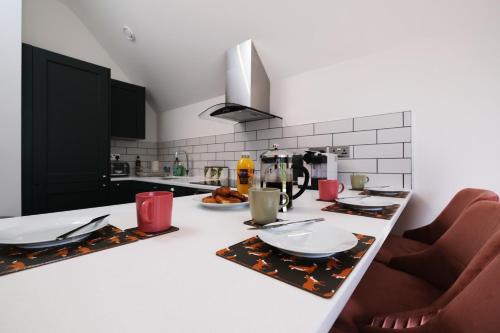 eine Küche mit einer weißen Theke mit Tellern und Küchenutensilien in der Unterkunft Beautiful One Bedroom Penthouse in London