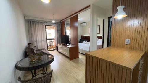 a living room with a table and a bedroom at Flat beira lago no centro de BSB in Brasilia