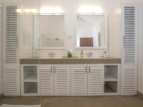 La salle de bains blanche est pourvue d'un lavabo et d'un miroir. dans l'établissement Andiramada Walawwa, à Rambukkana