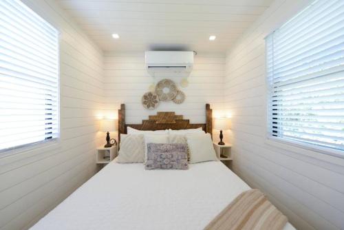 a bedroom with a bed with white walls and windows at New Luxury Shipping Container in Bellmead