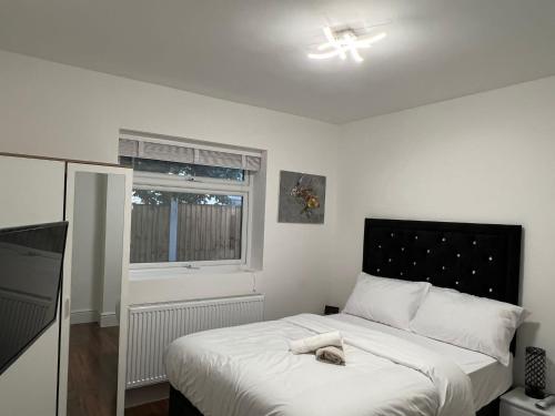 1 dormitorio con 1 cama con colcha blanca y ventana en Nikoda Lodge en Gillingham