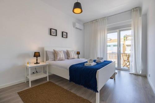 a white bedroom with a bed and a balcony at Urban Elegance Apartment in Almada