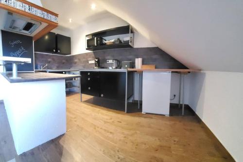 een keuken met zwarte kasten en een houten vloer bij 100 qm DG Wohnung 《Kehr wieder》Bexbach Saarland in Bexbach