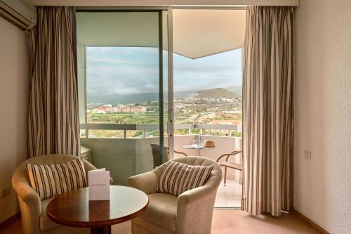 Habitación con 2 sillas, mesa y ventana grande. en Precise Resort Tenerife en Puerto de la Cruz