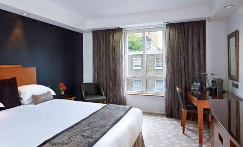 a hotel room with a bed and a desk and a window at Park Plaza Victoria London in London