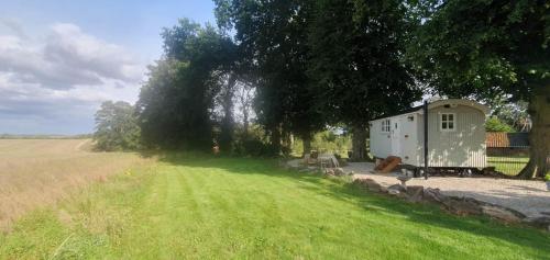 a small shed in the middle of a grass field at Church House Hut in Melton Mowbray