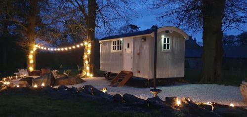 a tiny house with lights in a yard at night at Church House Hut in Melton Mowbray
