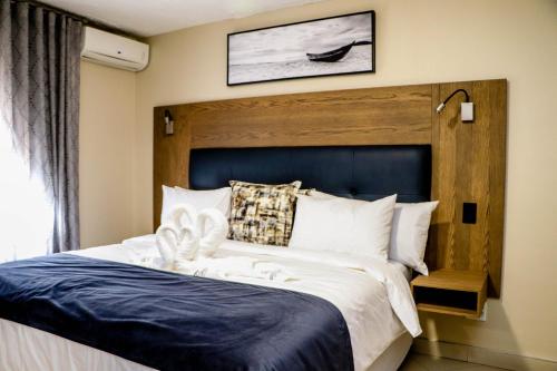 Windhoek Gardens Boutique Hotel في ويندهوك: غرفة نوم مع سرير كبير مع اللوح الأمامي الأزرق