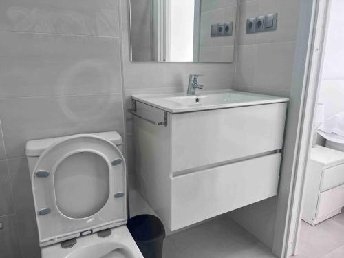 La salle de bains blanche est pourvue de toilettes et d'un lavabo. dans l'établissement Apartamento cerca de la playa, Torre Del Mar, à Torre del Mar
