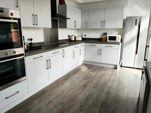 a kitchen with white cabinets and a wooden floor at Wentworth Road Accomodation in Doncaster