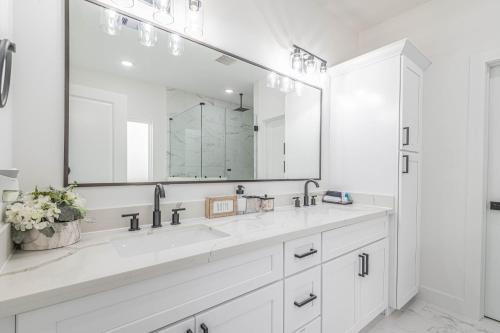 a white bathroom with two sinks and a large mirror at New! Houston Luxury Haven near Dwtn, Med CTR in Houston