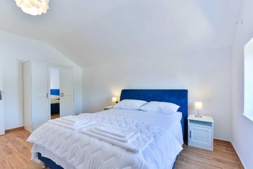 um quarto com uma grande cama branca e uma cabeceira azul em Villa Natura with pool, Zadar county em Stankovci