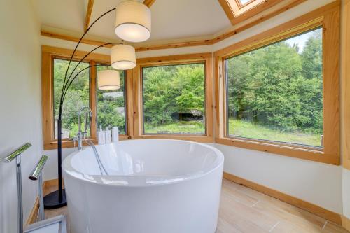 a large white tub in a bathroom with windows at Catskills Mountain Cabin in Bloomville! in Stamford