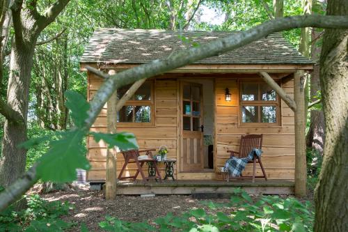 a wooden cabin in the woods with a table and chairs at West Stow Pods in Bury St Edmunds in West Stow