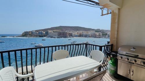 a balcony with a grill and a table and chairs at Seaview Apartment in Żebbuġ