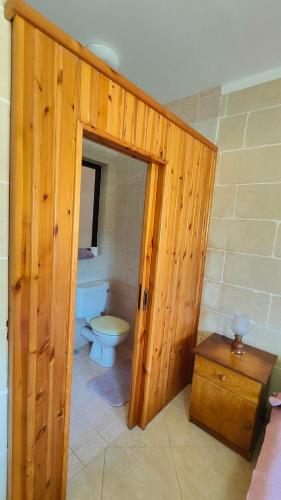 a bathroom with a toilet and a wooden door at Seaview Apartment in Żebbuġ