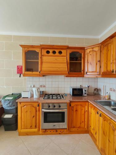 a kitchen with wooden cabinets and a stove top oven at Seaview Apartment in Żebbuġ