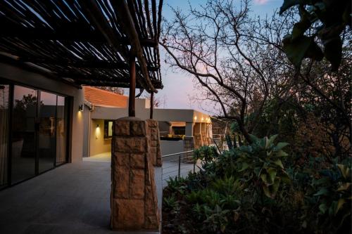 a house with a stone pillar in the yard at Elements Bush Villa 295 in Mabula