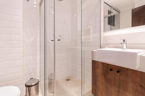 a white bathroom with a sink and a shower at 360 Liberdade in Sao Paulo