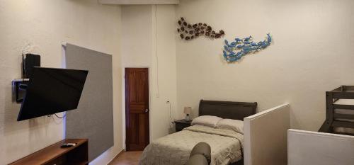 - une chambre avec un lit et une télévision murale dans l'établissement Casa Yorba, à Jacó