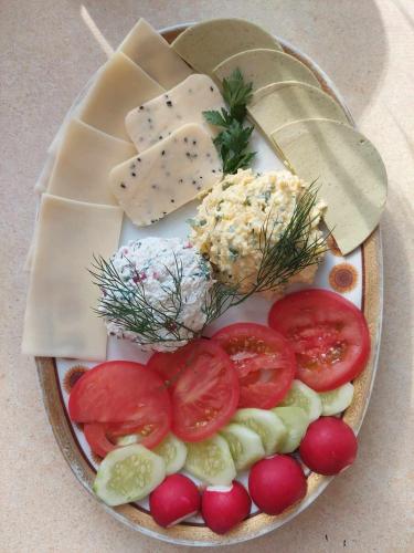 a plate of food with tomatoes cucumbers and cheese at Żurawi Staw- siedlisko obok Augustowa in Augustów