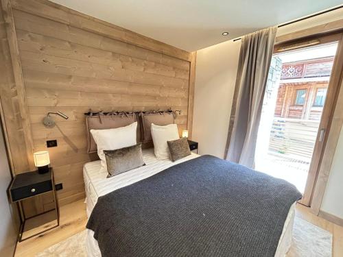 une chambre avec un grand lit avec un mur en bois dans l'établissement Les Gets - Appartement prestige avec grande terrasse, proche centre et pistes - FR-1-623-342, aux Gets