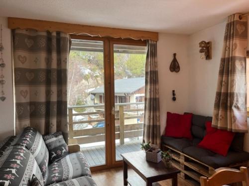 a living room with a couch and a balcony at Le chalet d'Isis in Villarodin-Bourget