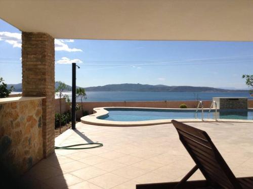 un patio con piscina y vistas al agua en Spacious Villa With a Pool, en Nea Peramos