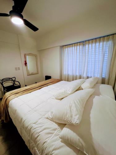 sypialnia z dużym białym łóżkiem i oknem w obiekcie Departamento Catedral w mieście Santa Rosa