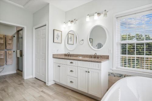 a white bathroom with a sink and two mirrors at The Powell at Ships Watch in Duck
