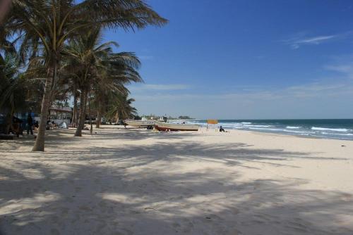 uma praia arenosa com palmeiras e o oceano em Aquaview Amina's rental apartment em Bijilo