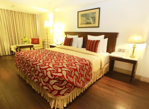 a hotel room with a large bed with a red blanket at The Ashok, New Delhi in New Delhi