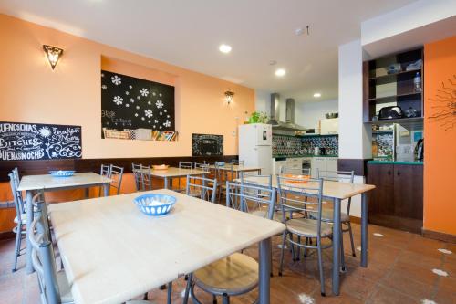 a restaurant with tables and chairs and a kitchen at Oasis Backpackers' Hostel Granada in Granada