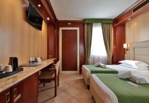 a hotel room with two beds and a desk at Best Western Hotel Anthurium in Santo Stefano al Mare