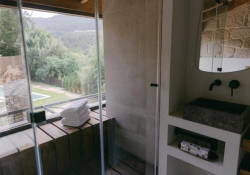 a bathroom with a glass shower with a window at Numa Experimental in Pontevedra