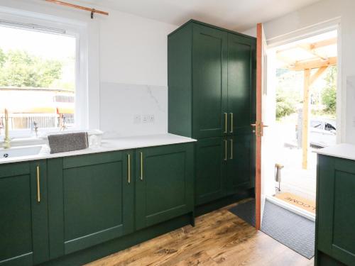 una cocina con armarios verdes y fregadero en 1 Slatach, en Glenfinnan
