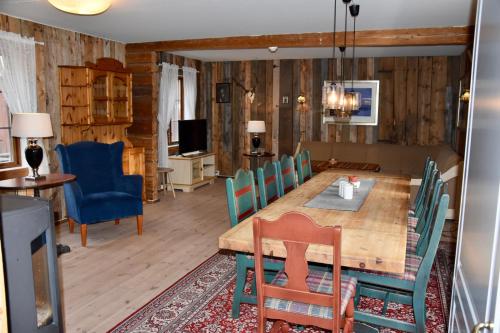 a dining room with a wooden table and blue chairs at Nedre Stensgården in Røros