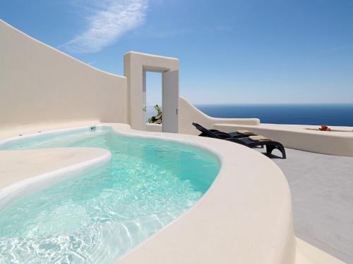 una piscina in una casa con l'oceano sullo sfondo di Dome Santorini Resort a Imerovigli