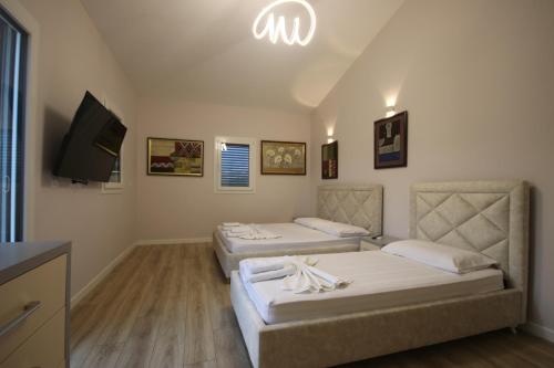 a room with two beds and a flat screen tv at Vila Mario Himare in Himare