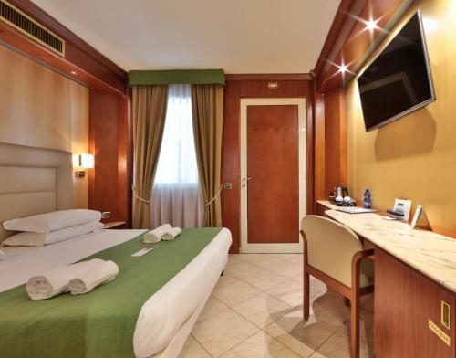 サント・ステーファノ・アル・マーレにあるベスト ウェスタン ホテル アンスリウムのベッドとデスクが備わるホテルルームです。