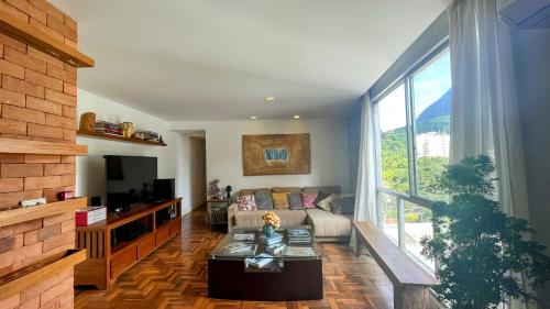 uma sala de estar com um sofá e uma janela grande em Amplo e iluminado apartamento na Gávea no Rio de Janeiro
