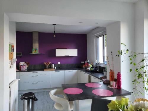 a kitchen with purple walls and a table with pink circles at L'instant présent - Chambre Ambre in Salbris