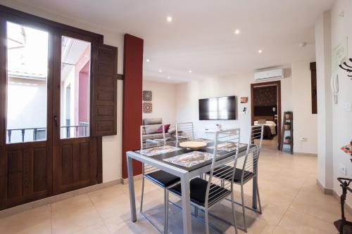 cocina y comedor con mesa de cristal y sillas en Apartamentos Reyes Católicos, en Granada