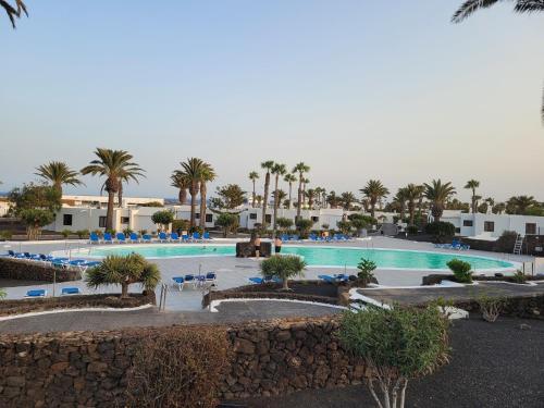 een groot zwembad met palmbomen en gebouwen bij Casa Tanja Casas del Sol in Playa Blanca