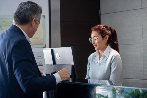 a man and a woman standing in front of a computer at Aku Hotels in Lima