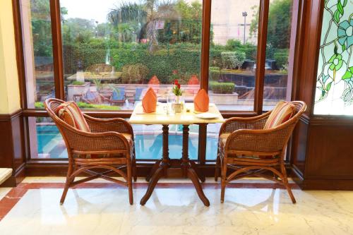 a table and three chairs in a room with a window at The Ashok, New Delhi in New Delhi