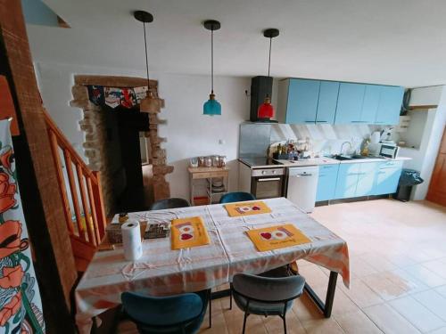 cocina con mesa y sillas y cocina con armarios azules en Lovely farm house, en Pouligny-Notre-Dame